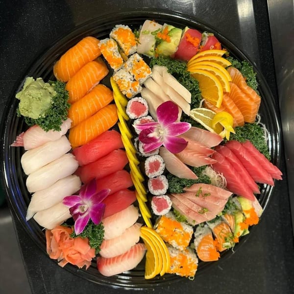 A large platter of Flame Sushi Japanese Grill's sushi and sashimi, garnished with orchids and citrus.
